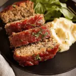 Delicious old fashioned meatloaf slice served with creamy mashed potatoes and green beans, perfect comfort food dish.